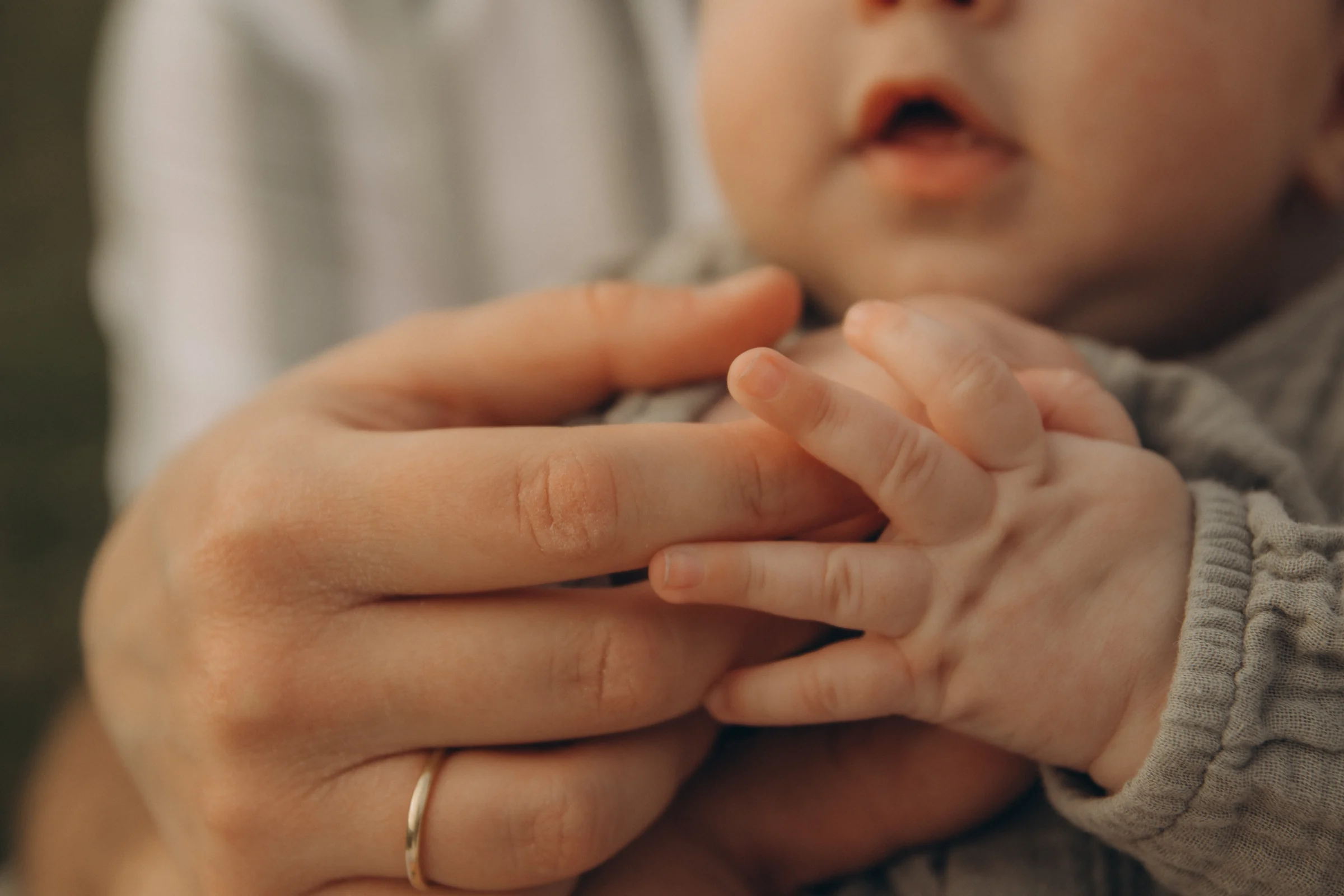 Babyhände greifen nach den Fingern der Eltern